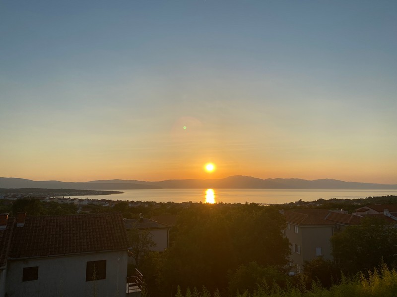 Ett sovrum med dubbelsäng och fönster i fastighet H1383 på ön Krk.