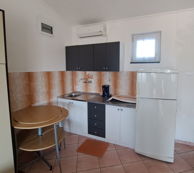 Köksdel med litet bord och kylskåp.