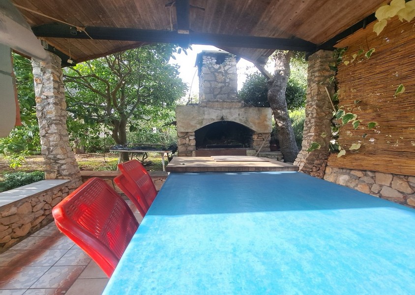 Uteplats med grill, bord och röda stolar.