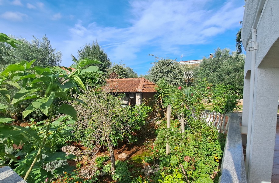 Trädgårdsutsikt med träd och ett litet stenhus.