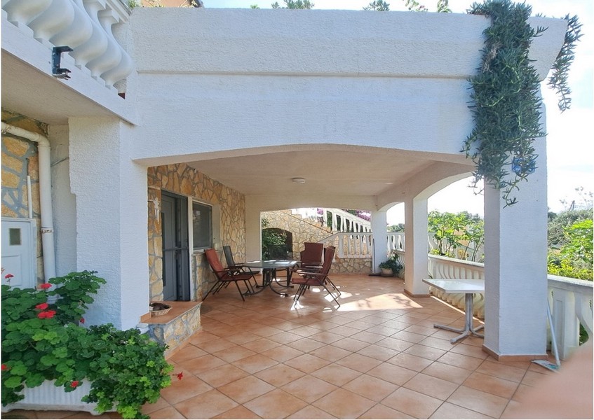 Täckt terrass med sittplatser och växter.