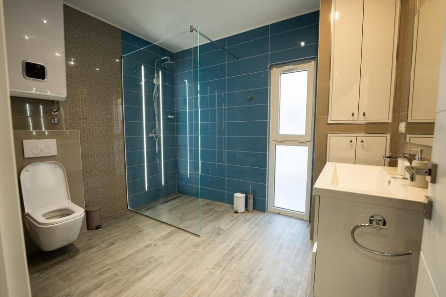 Stort badrum med duschkabin och blått kakel