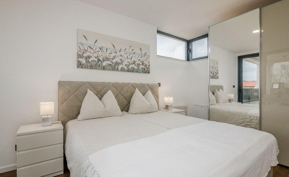 Ljust sovrum med dubbelsäng och spegelskåp