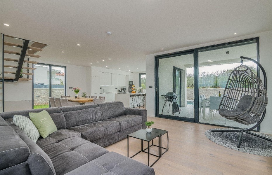 Öppet vardagsrum med soffa, hängstol och kök