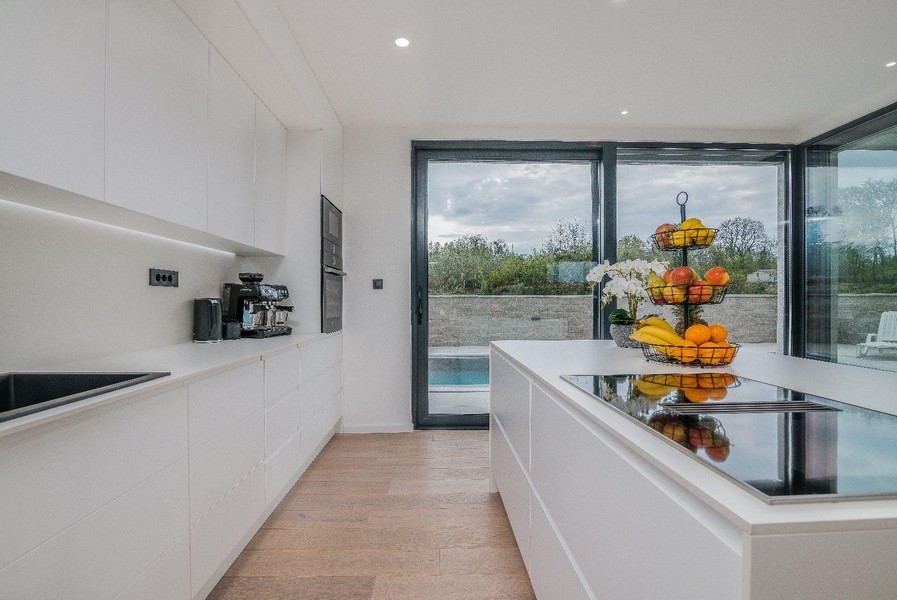 Modernt vitt kök med utsikt över ön och poolen