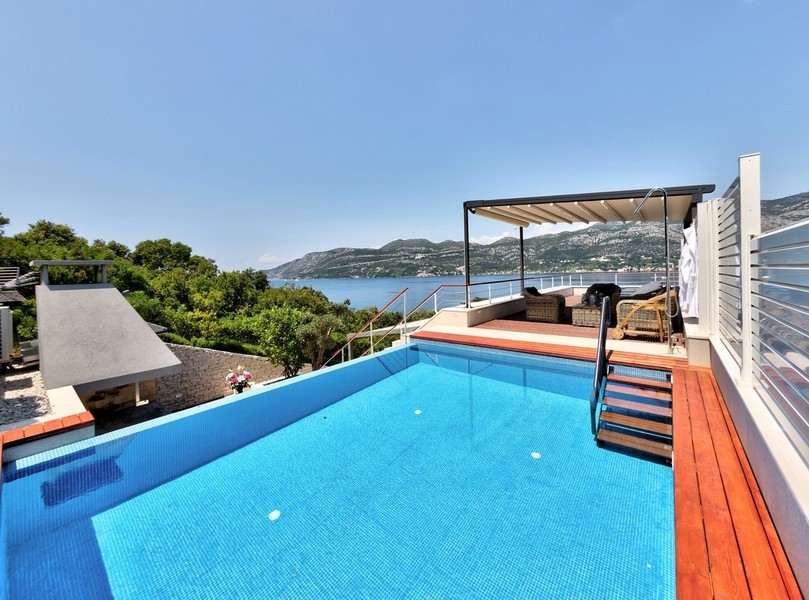 Infinitypool med havsutsikt och täckt lounge