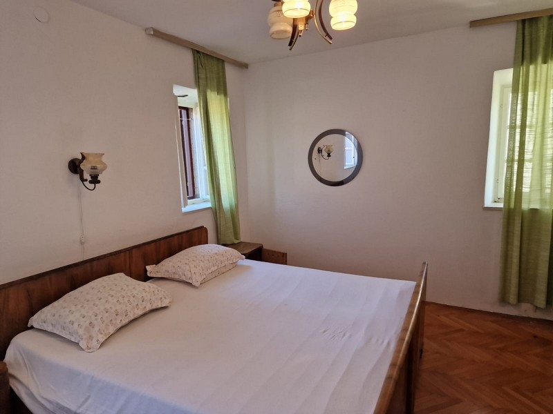 Sovrum med dubbelsäng, träram och gröna gardiner