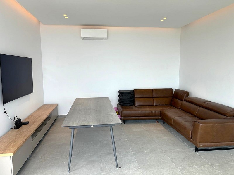 Vardagsrum med skinnsoffa och vägghängd TV