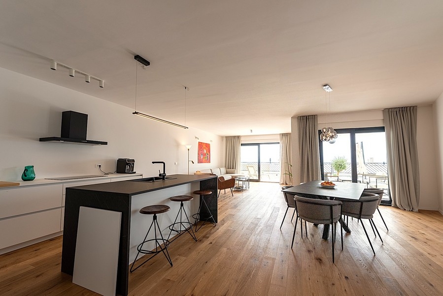 Modernt kök med ö, matplats och vardagsrum i bakgrunden