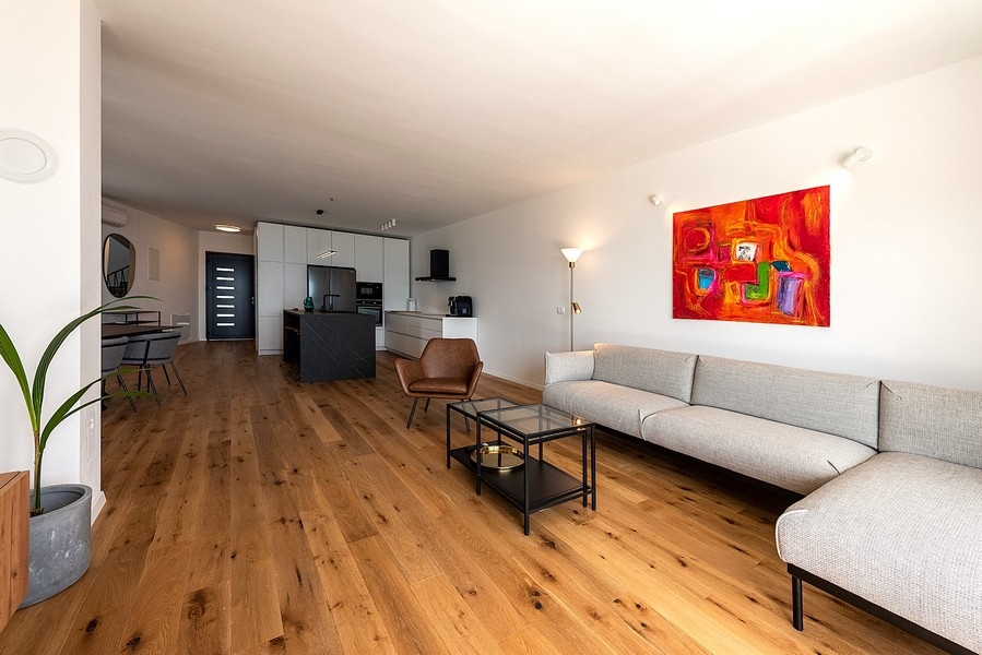 Modernt vardagsrum med stor soffa, TV och utgång till terrassen