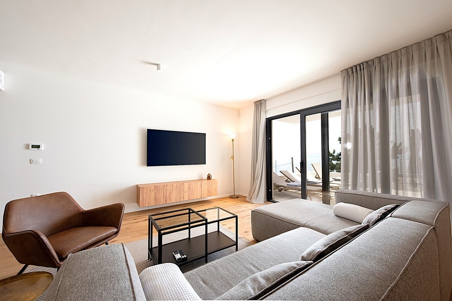 Vardagsrum med grå soffa, TV och utgång till altan