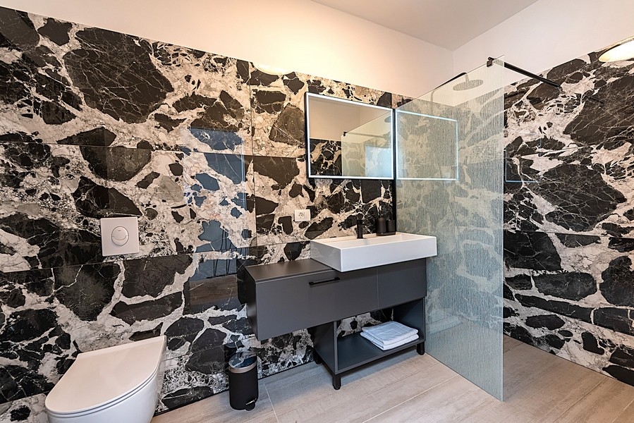 Modernt badrum med svart marmorvägg och duschkabin