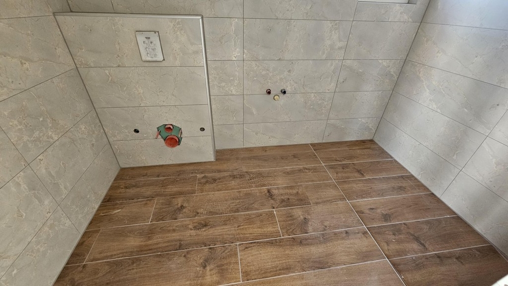 Badrum med modernt kakel och golv i trälook