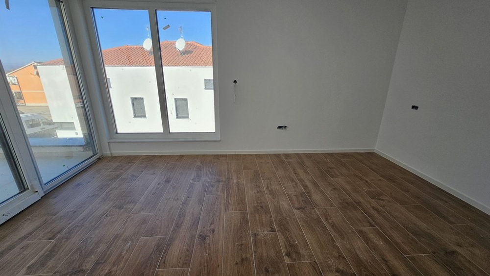 Sovrum med fönster från golv till tak och trägolv