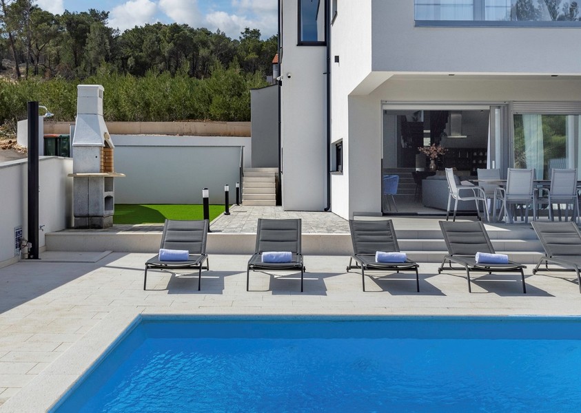 Pool, solterrass och utsikt över grillen.
