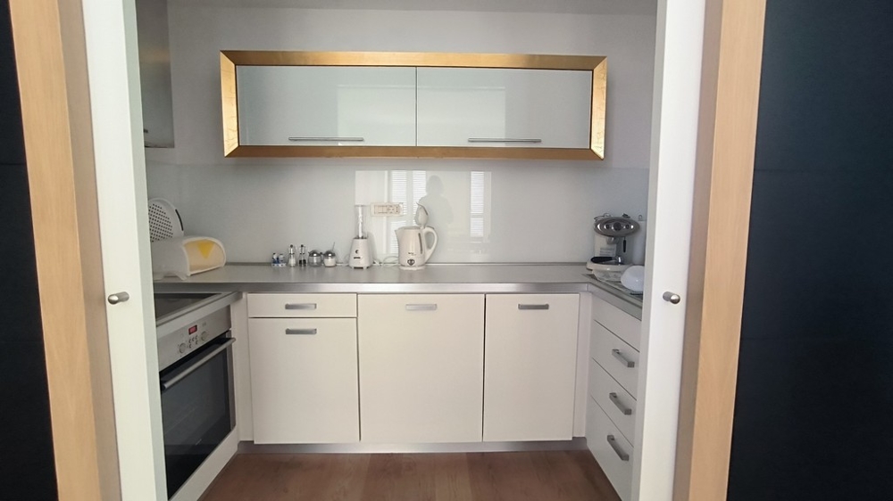 Kompakt kök med vita inbyggda möbler och gulddetaljer