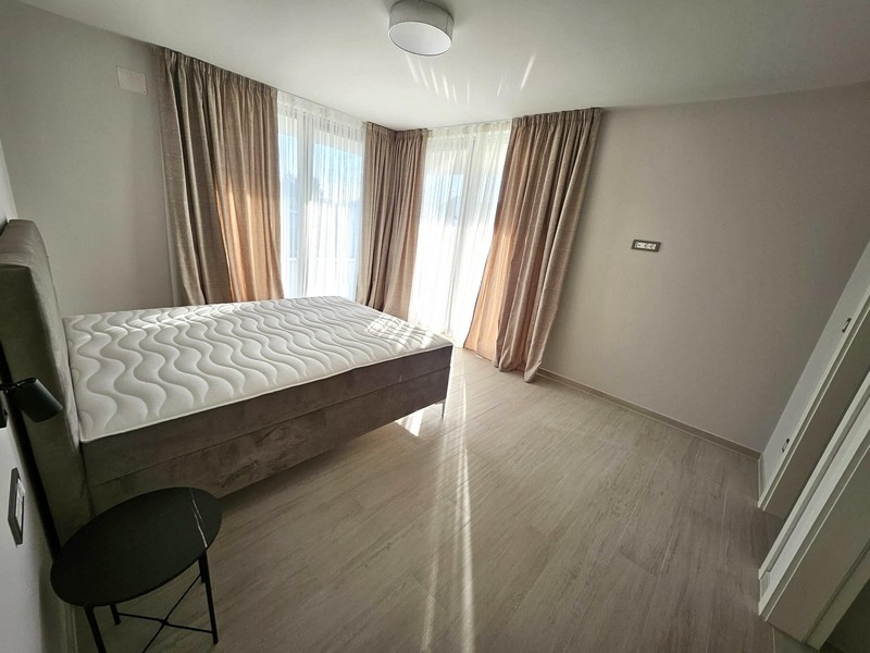 Ljust sovrum med dubbelsäng, gardiner och balkongdörrar