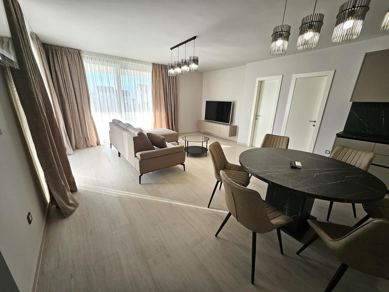 Ljust vardagsrum med soffgrupp och TV, stora fönster