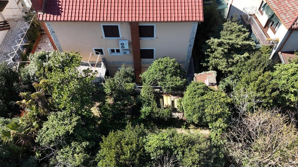 Vy bakifrån av huset med grön trädgård och sittgrupp