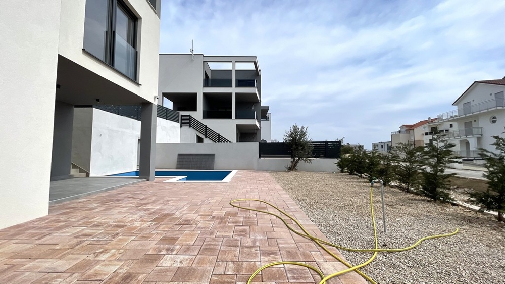 Modern terrass med poolområde och asfalterad uteplats