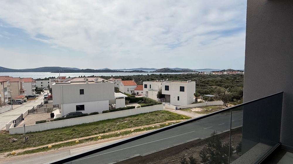 Havsutsikt från balkong över bostadsområde och kustlandskap