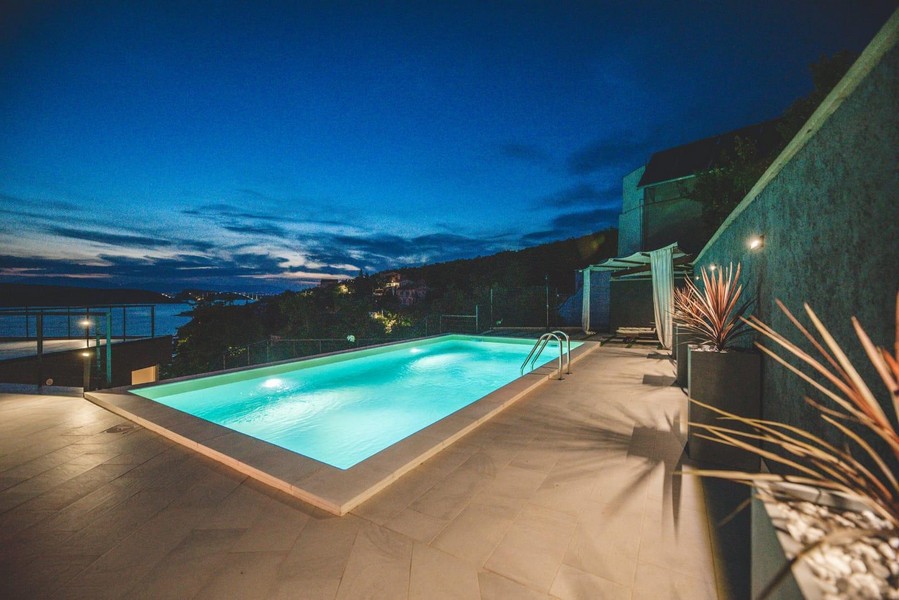 Poolterrass med havsutsikt på natten