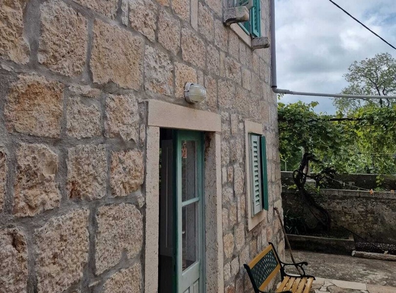 Stenfasad med entré och fönsterluckor