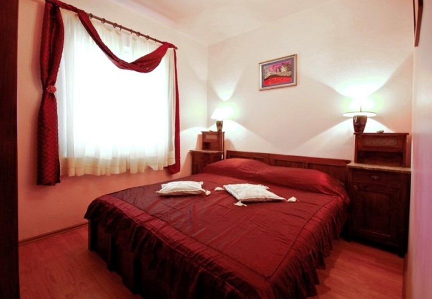 Sovrum med dubbelsäng och röda sängkläder