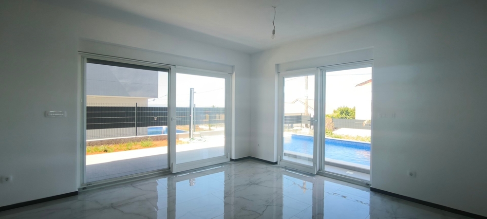 Vardagsrum och utsikt över poolen på fastigheten H3574.