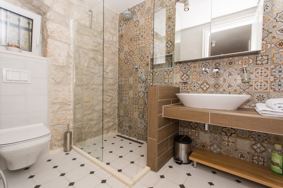 Badrum med dusch, bidé och mönstrat väggkakel