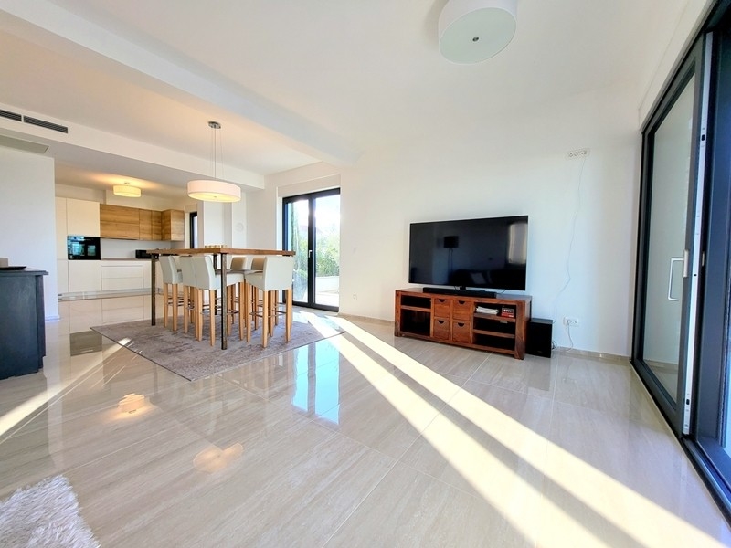 Ljust vardagsrum med TV och utgång till altan