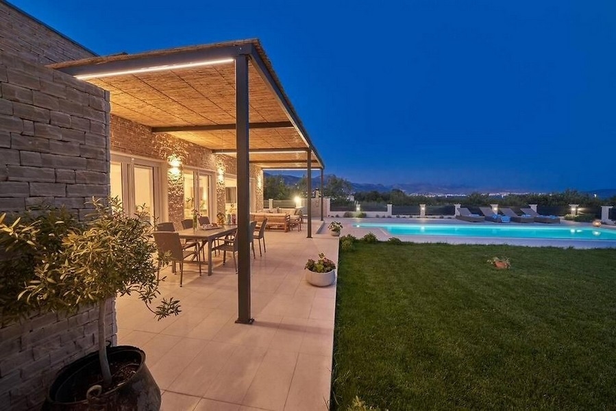 Täckt terrass med trädgård och pool på natten