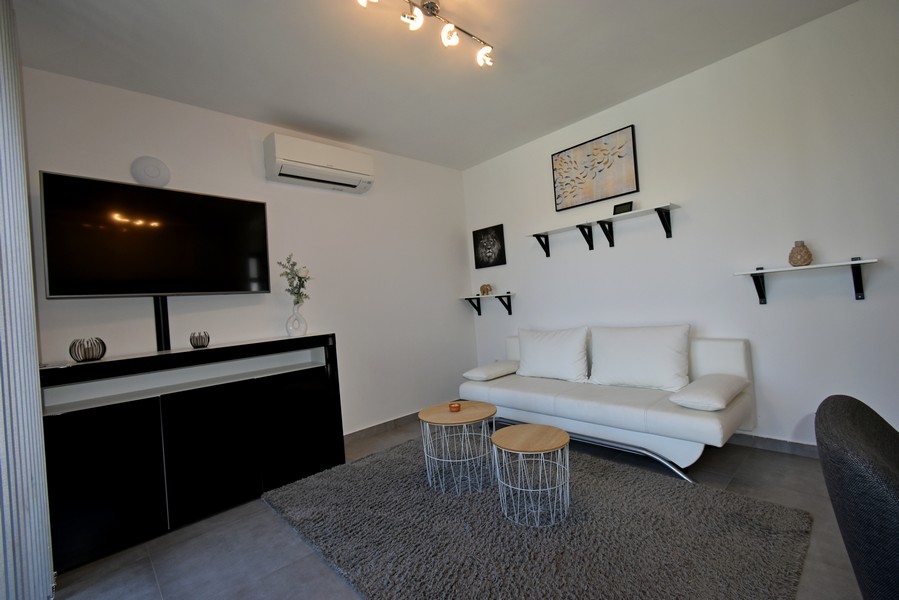 Vardagsrum med soffa, TV och luftkonditionering