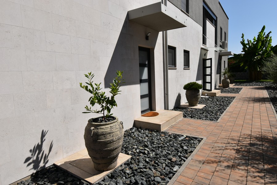 Entré med asfalterad stig och prydnadsväxter