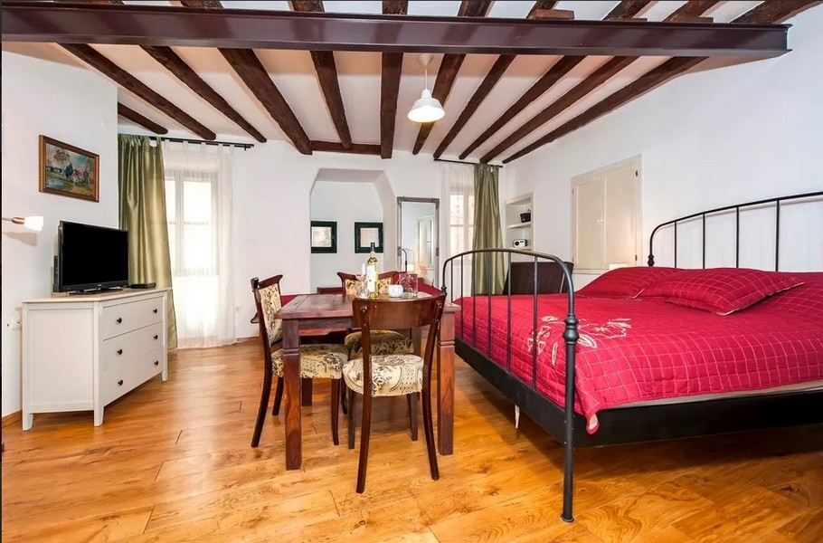 Ljus lägenhet med säng, träbjälkar och bord