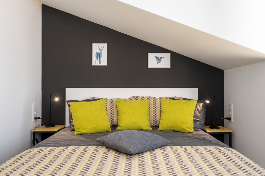 Vindsrum med dubbelsäng och gula kuddar