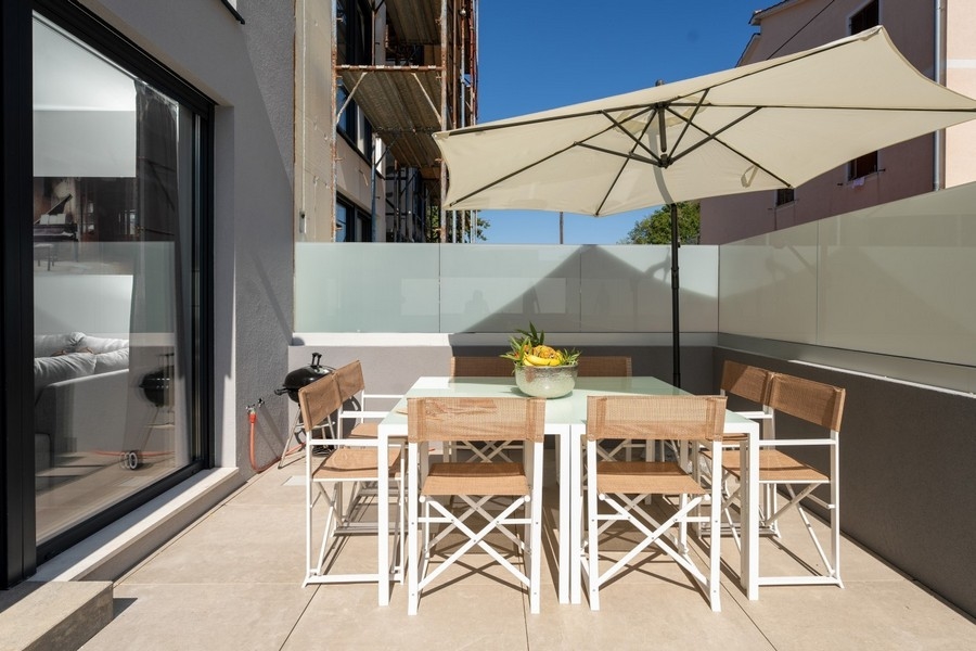 Terrass med matbord och parasoll