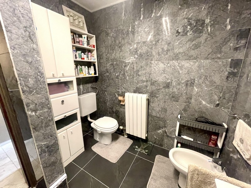 Badrum med wc, bidé och grått väggkakel