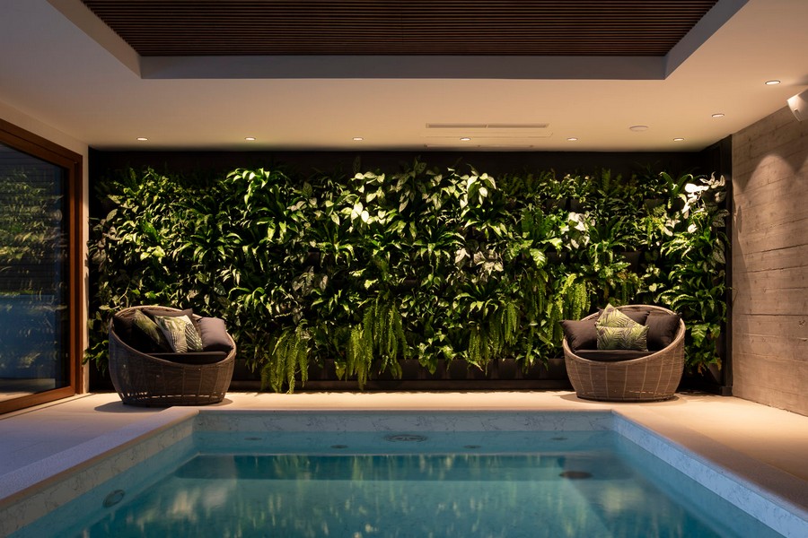 Inomhuspool med grön växtvägg och sittgrupp