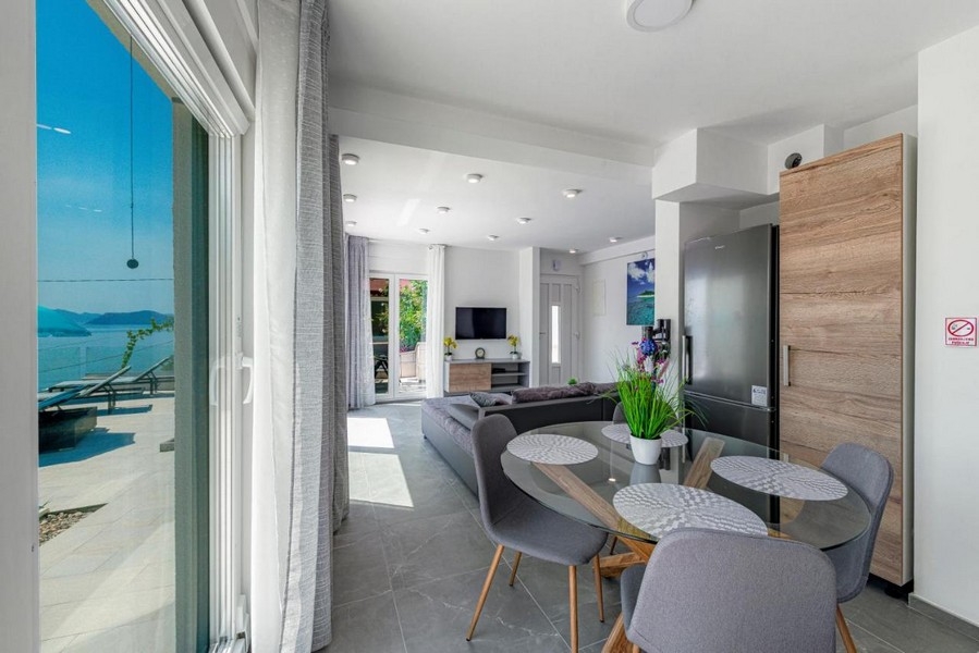 Matplats med glasbord och tillgång till terrassen med havsutsikt