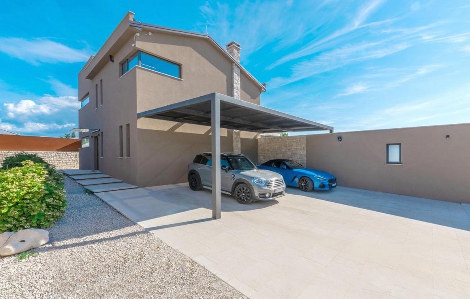 Täckt carport med två bilar framför villan