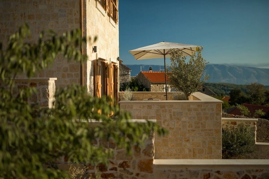 Stenhus med terrass och parasoll, utsikt över bergen