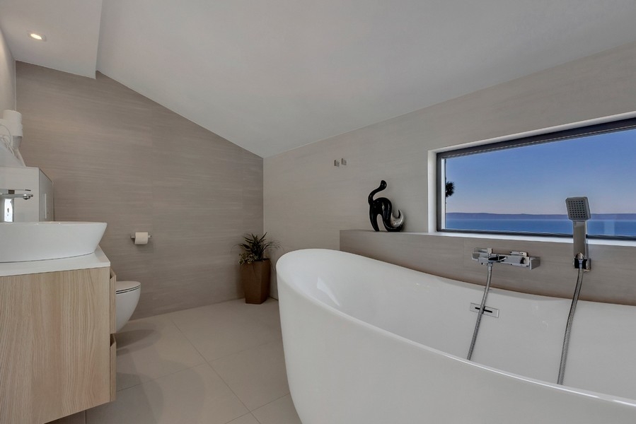 Modernt badrum med fristående badkar och havsutsikt