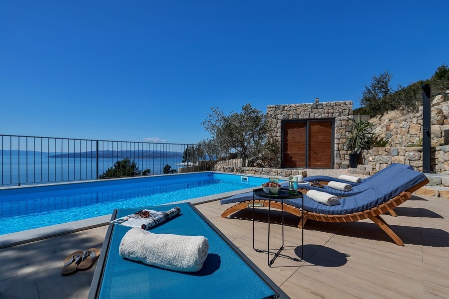 Pool med solstolar och havsutsikt