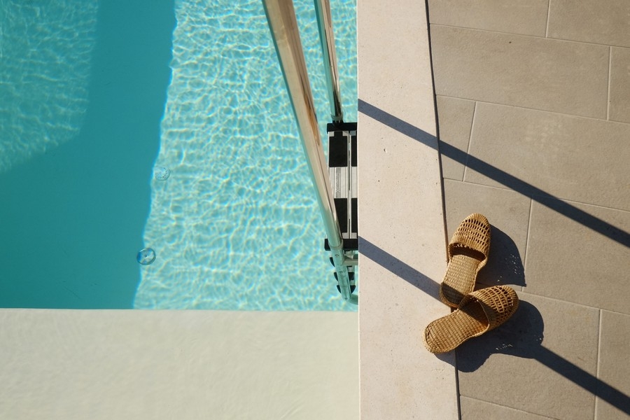 Pooldetalj med solljus och sandaler