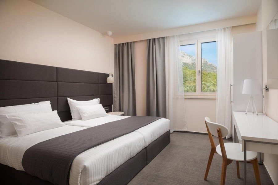 Ljust sovrum med dubbelsäng och utsikt över bergen