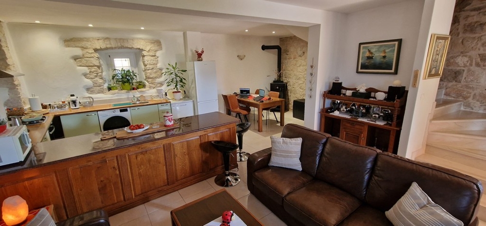 Vardagsrum med kök, matplats och naturstensvägg