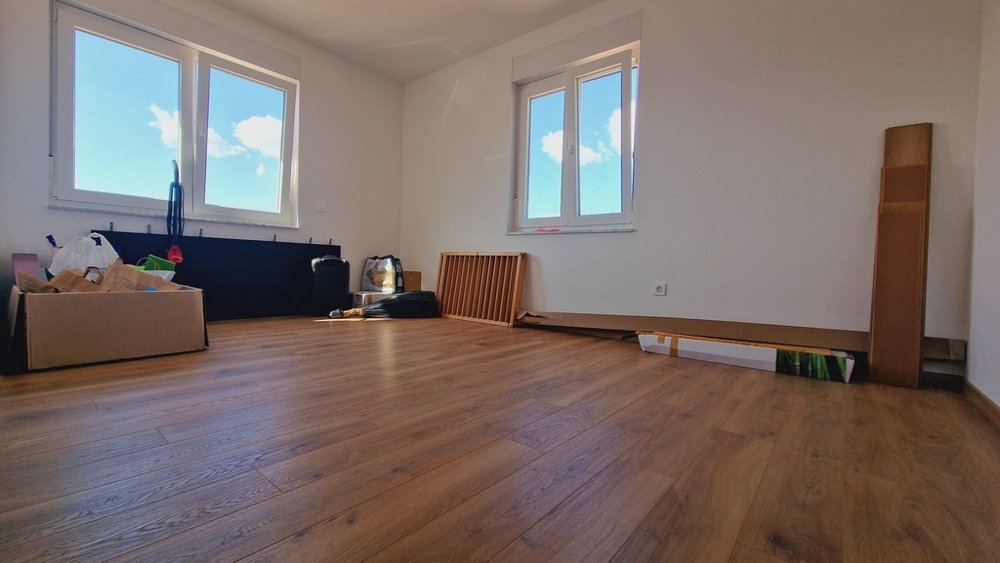 Sovrum med parkettgolv och stora fönster