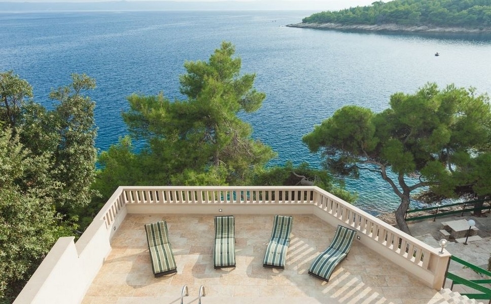 Solterrass med solstolar och panoramautsikt över havet