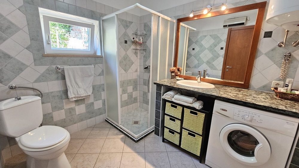 Badrum med dusch, handfat och tvättmaskin